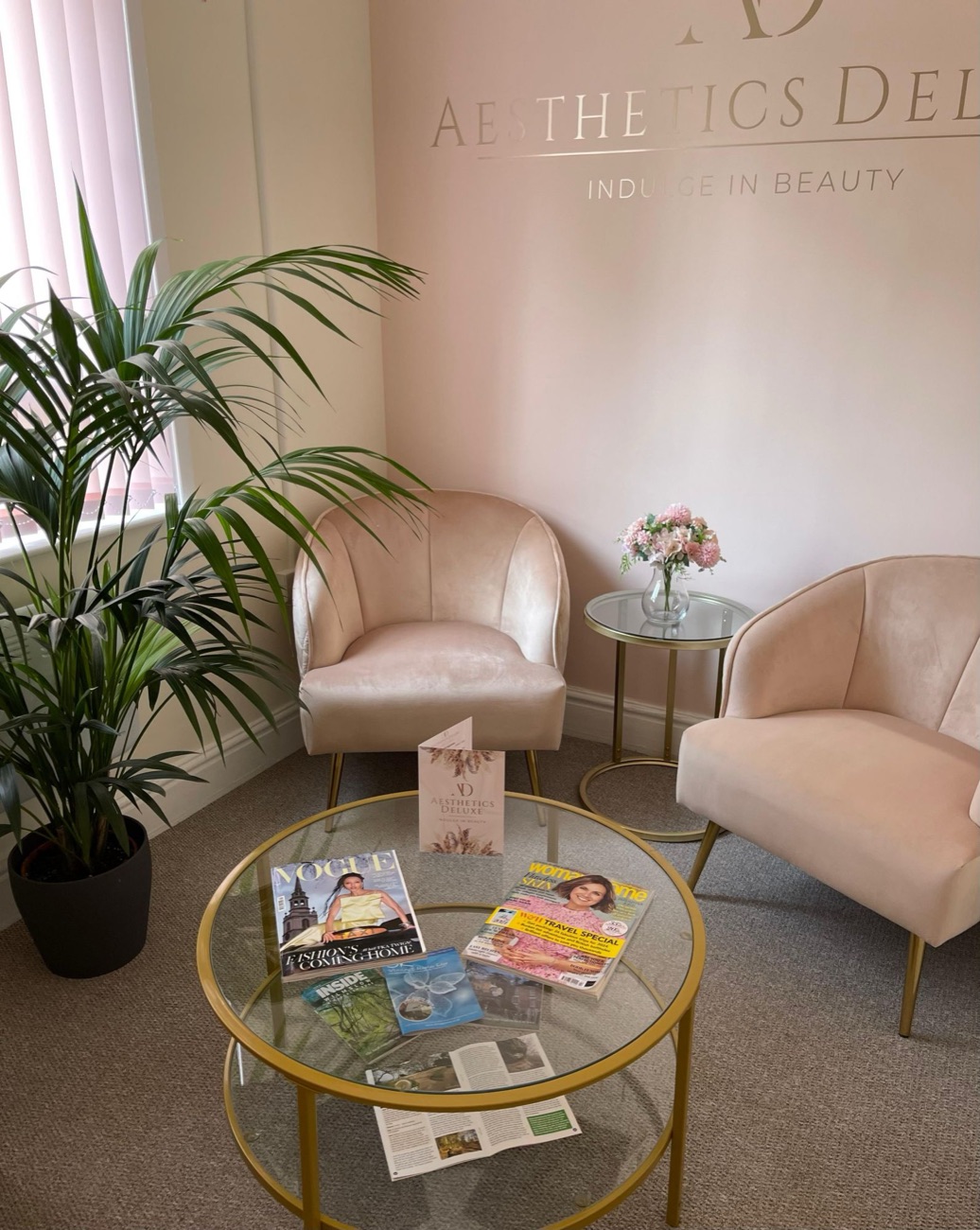 The Aesthetics Deluxe waiting room, with velvet chairs and the gold clinic logo on the wall